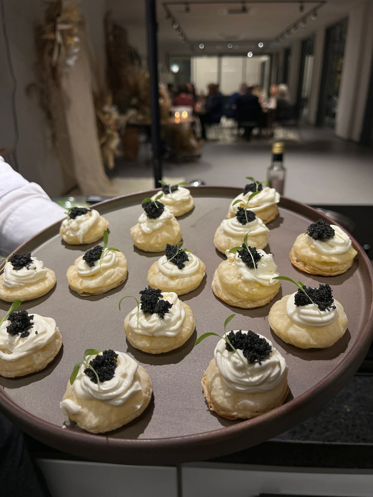 Garçom servindo uma bandeja de canapés com creme e caviar